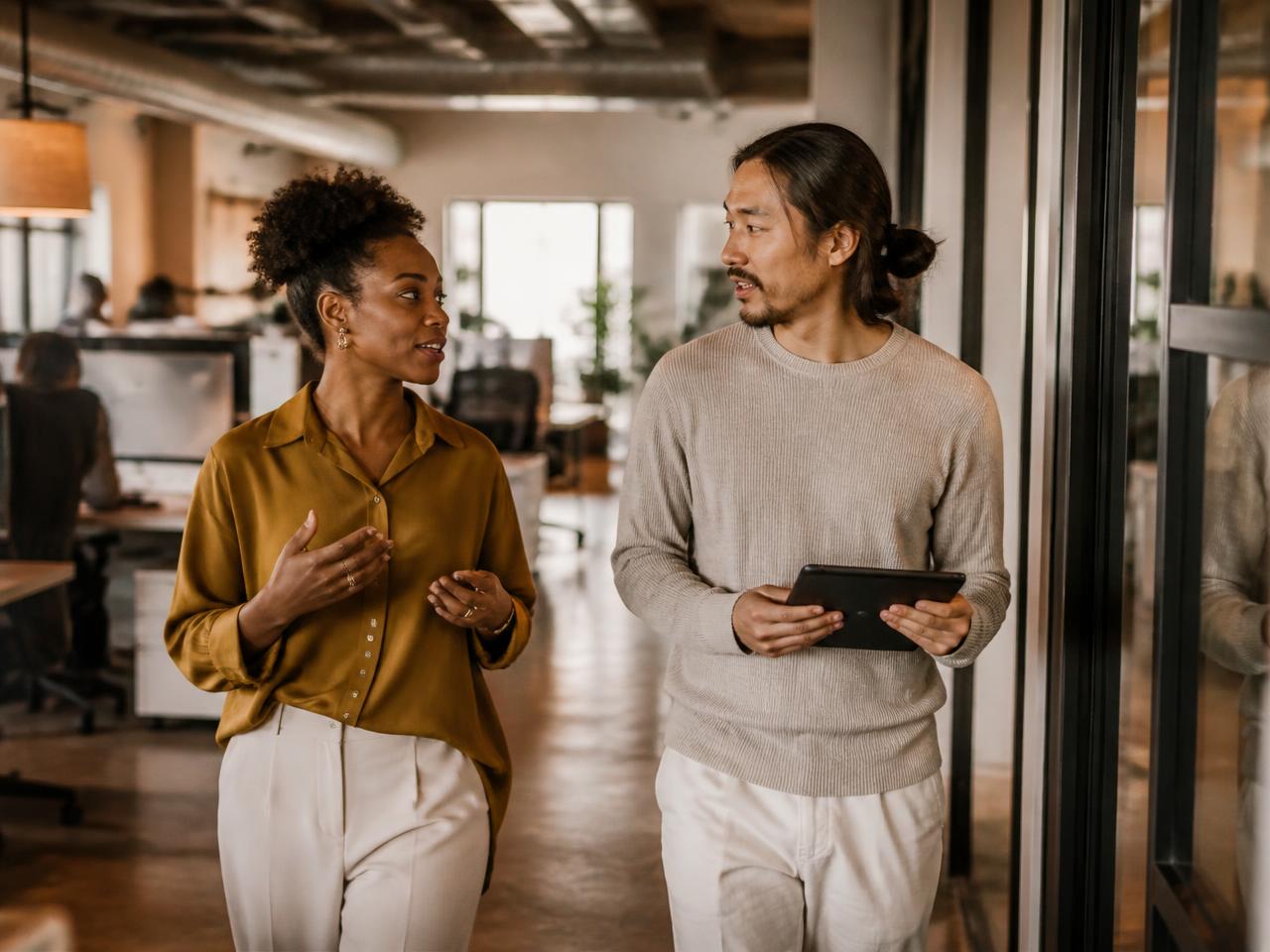 Two colleagues talking while walking through an office